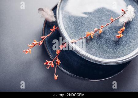 Set of handmade round ceramic plates decorated with spring branches and feathers. Close up of lacquered blue vintage dishes on grey background. Stylis Stock Photo
