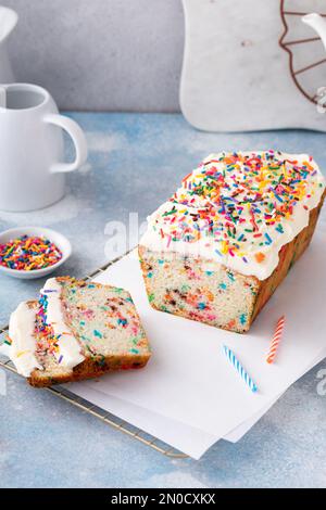 Birthday cake or funfetti pound cake with sprinkles and frosting sliced with birthday candles Stock Photo