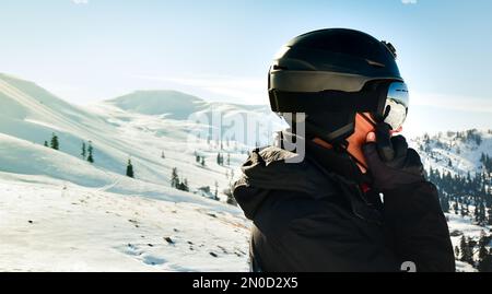 Excited skier man in black jacket ski goggles mask text friends shot on mobile phone spend weekend winter in mountains isolated on purple background. Stock Photo