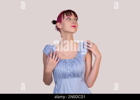 teenager girl in a blue dress dreamily looks up on a light background Stock Photo