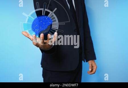Businessman holding digital image of brain in hand on blue background, closeup Machine learning concept Stock Photo