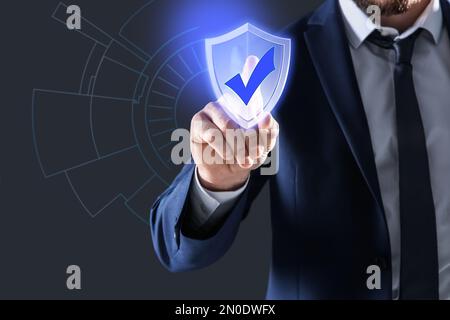 Cyber insurance concept. Man using virtual screen with shield illustration as symbol of protection, closeup Stock Photo