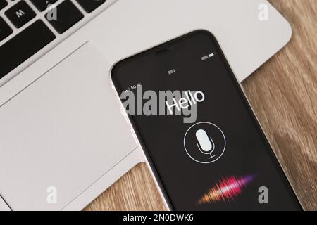 Smartphone with activated voice search app and laptop on wooden table, closeup Stock Photo