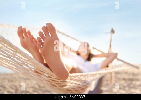 Young woman relaxing in hammock outdoors, focus on legs Stock Photo