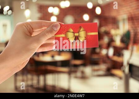 Woman holding gift card in restaurant, closeup Stock Photo