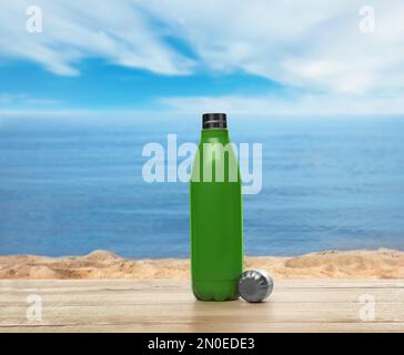 Thermo bottle on wooden table near sea under blue sky Stock Photo