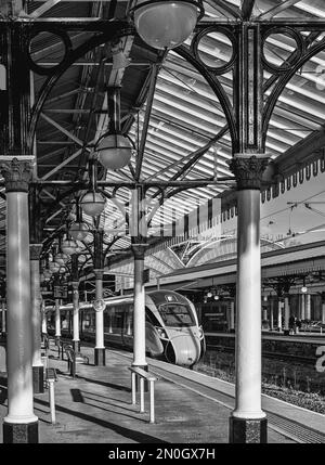 A locomotive rests beside a platform covered by a historic 19th Century ...