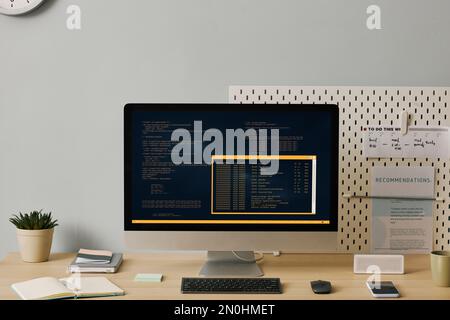 Front view background image of computer with code lines on screen in minimal home office setup Stock Photo