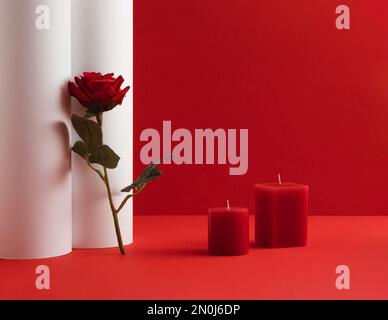 Romantic composition with candles and red rose flower on red and white background. Valentines Day idea. Copy space. Stock Photo