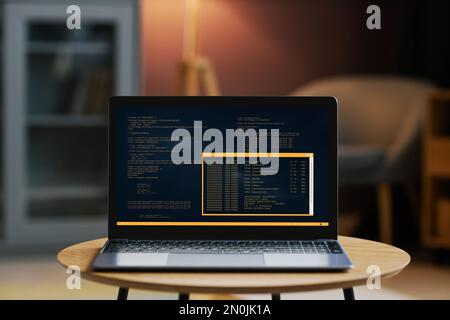 Background image of open laptop with code on screen in dim home interior Stock Photo