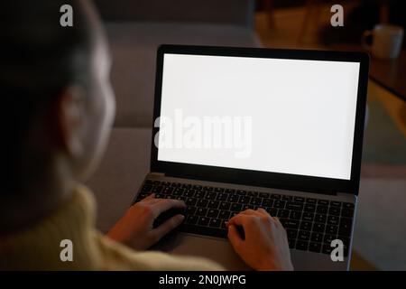 Closeup of woman using laptop with white screen in dark home setting, copy space Stock Photo