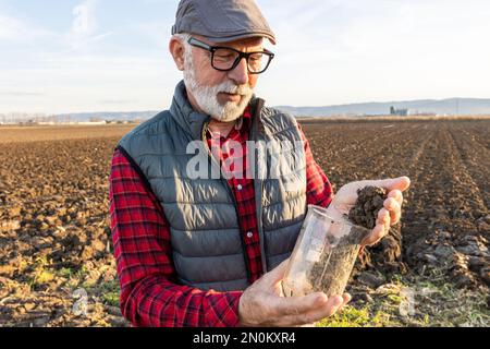 Mature farmer checking soil quality in field in autumn time Stock Photo