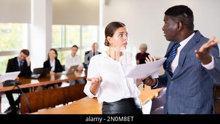 Middle aged african american male boss dismissing a young white brunette female worker Stock Photo