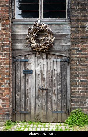 Wooden door with an antler and pine cone wreath, close up Stock Photo