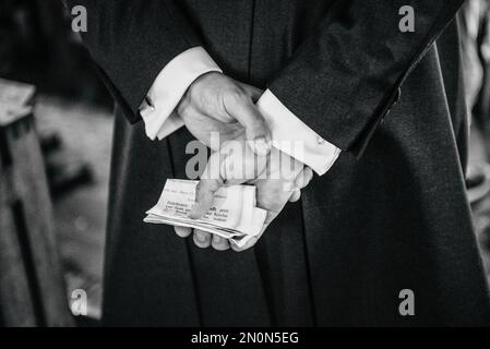 A greyscale back view of a person holding papers with notes behind his back Stock Photo