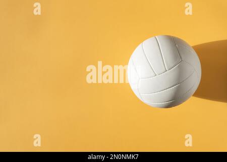 White volleyball leather ball on yellow background. Top view. Game equipment horizontal sport theme poster, greeting cards, headers, website and app Stock Photo