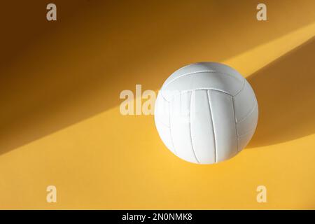 White volleyball leather ball on yellow background. Top view. Game equipment horizontal sport theme poster, greeting cards, headers, website and app Stock Photo