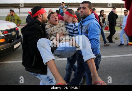 Palestinian protesters evacuate a wounded youth during clashes with Israeli soldiers securing the entrance of Erez border crossing between Gaza Strip and Israel, Friday, Dec. 11, 2015. (AP Photo/Adel Hana)