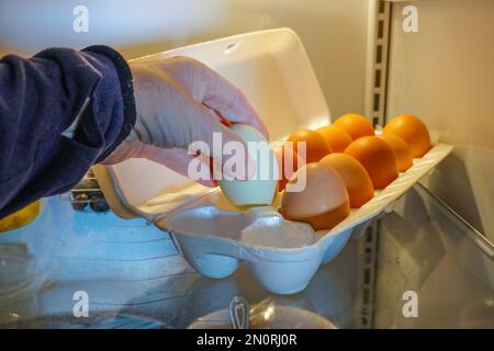 Woman taking egg from box of free range Fresh Chickens  eggs in a fridge Stock Photo