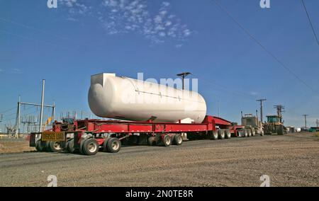 Rubber track tractor assist truck tractor transporting/pulling lowboy trailer with jeep & pup, hauling Siemens generator for Wind Turbine System. Stock Photo