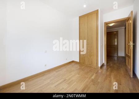 An empty bedroom with a built-in wardrobe with two folding oak doors Stock Photo