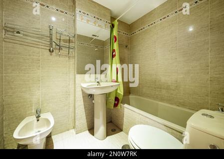 bathroom with bathtub, rectangular mirror attached to the wall and green curtains in the shower Stock Photo