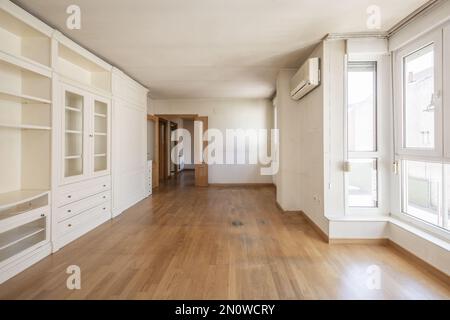 Living room of an empty house with a white lacquered wooden bookcase with drawers, shelves and cabinets Stock Photo