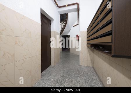 Renovated portal inside an old building with mailboxes and with wooden stairs and metal balustrade Stock Photo