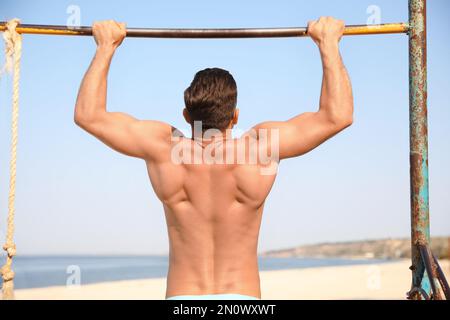 Man with slim body doing pull-ups Stock Photo