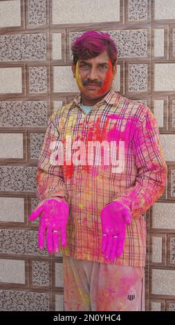 05 February 2023 Jaipur, Rajasthan, India. indian young man showing colourful palm and celebrating holi with colour splash Stock Photo