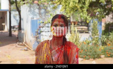 05 February 2023 Jaipur, Rajasthan, India. Beautiful young girl posing with exploding pink and yellow Holi powder around her Stock Photo