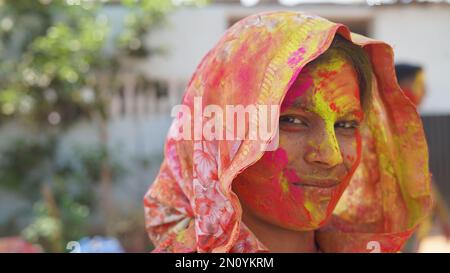 Young indian woman with color powder in her hand and with face coloured with gulal for festival of colours Holi Stock Photo