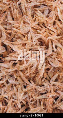 Plenty of dry shrimp background market for sell. Close-up pile texture detail bright light pink pale tone. Vertical format banner wallpaper cute Stock Photo