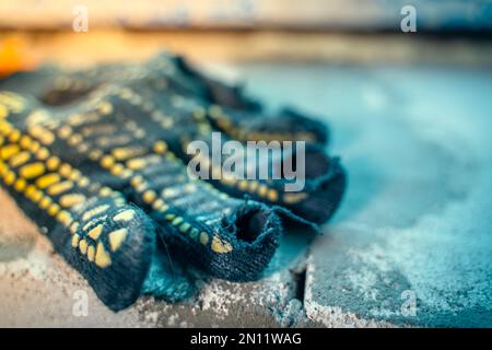 Close-up of a fabric construction glove with rubbed holes on the fingers. Rubberized Protective Worn Glove for Builder Handyman Stock Photo