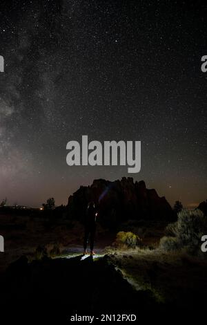 Young woman on a path shines torch, canyon against night sky, starry sky with Milky Way, Smith Rock State Park, Oregon, USA, North America Stock Photo