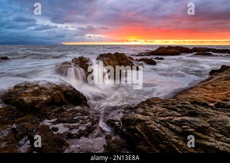 An Inspirational Ocean Sunset With Details In The Rocks And A Soft White Wave Coming To Shore High Resolution Stock Photo