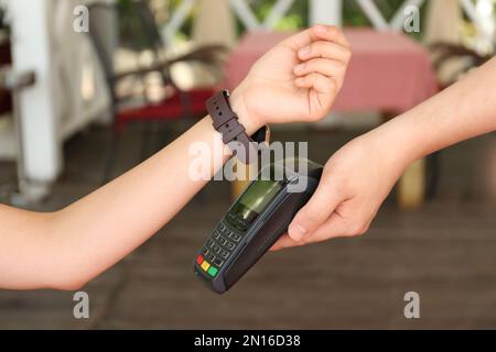 Woman using smartwatch for contactless payment in cafe, closeup Stock Photo