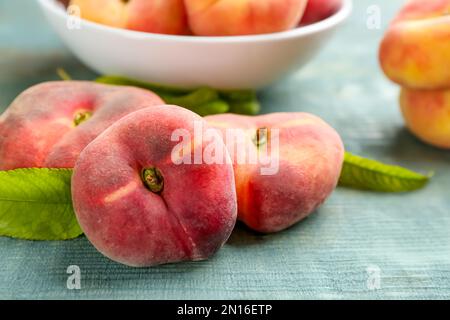 Fresh ripe donut peaches on light blue wooden table, closeup Stock Photo