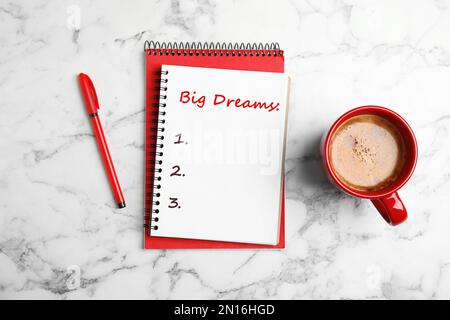 Notebook with dreams list on white marble table, flat lay Stock Photo