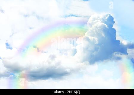 Fantasy world. Beautiful rainbow in sky with fluffy clouds Stock Photo