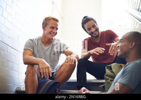 Living the university life. male university students sitting and talking before class. Stock Photo
