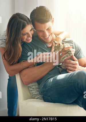 Youre such a cutie. a young couple sitting with their kitten at home. Stock Photo