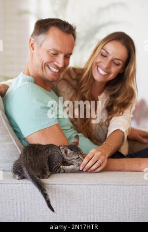 Enjoying a relaxed day together. a couple with their kitten at home. Stock Photo