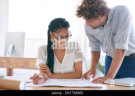 Working together for better results. two young designers working together in their office. Stock Photo