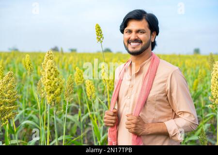 Portrait of happy young indian farmer couple touching wheat crop ...