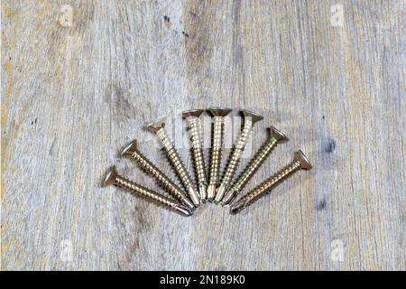 Self-drilling screws closeup isolated on wooden background. Stock Photo