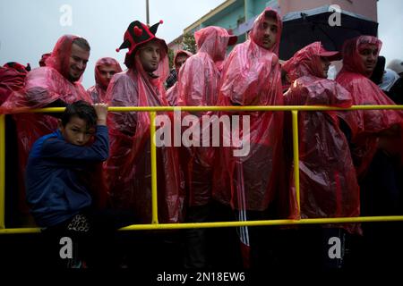 Baseball fans wearing ponchos wait during a rain delay prior to