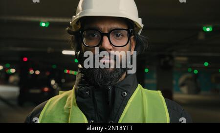 Portrait Indian Arabian bearded man in eyeglasses worker male engineer specialist of manufacture work. Business person in hard hat safety wear uniform Stock Photo