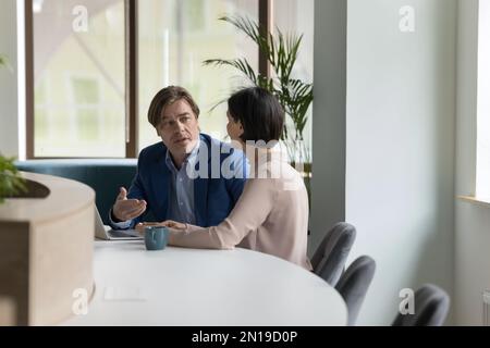 Two serious middle aged engaged business colleagues talking in office Stock Photo