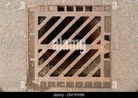 Close-up of sewer drain grate manhole made of steel metal on asphalt road as urban concept Stock Photo